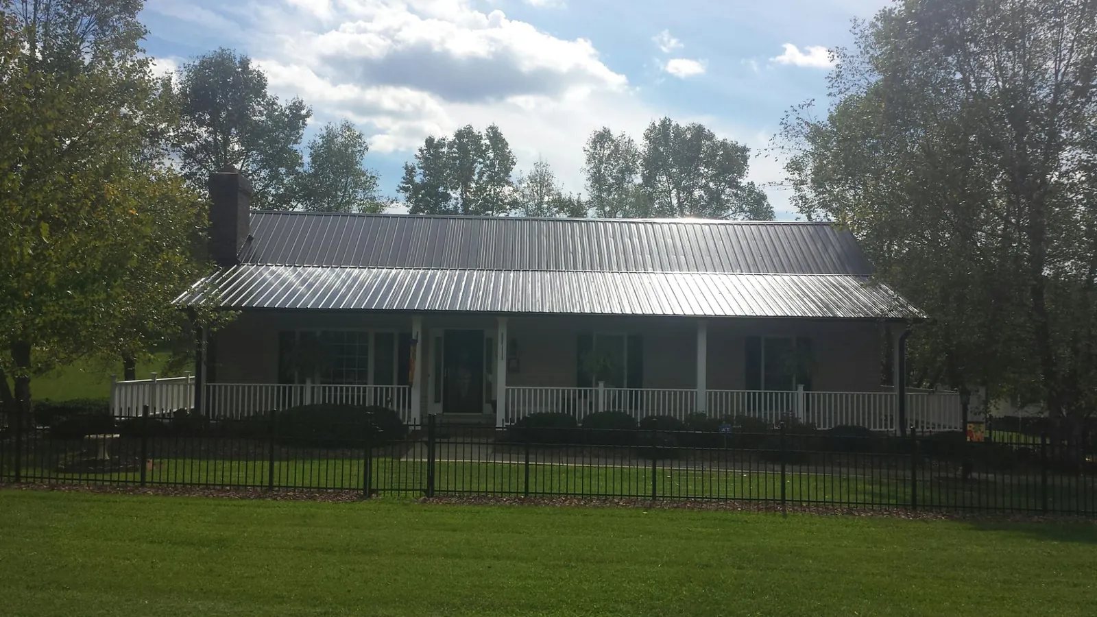 Gray metal roof on a brick ranch with a full width front porch — Gutter Guard Installation work by our crew in Alamosa