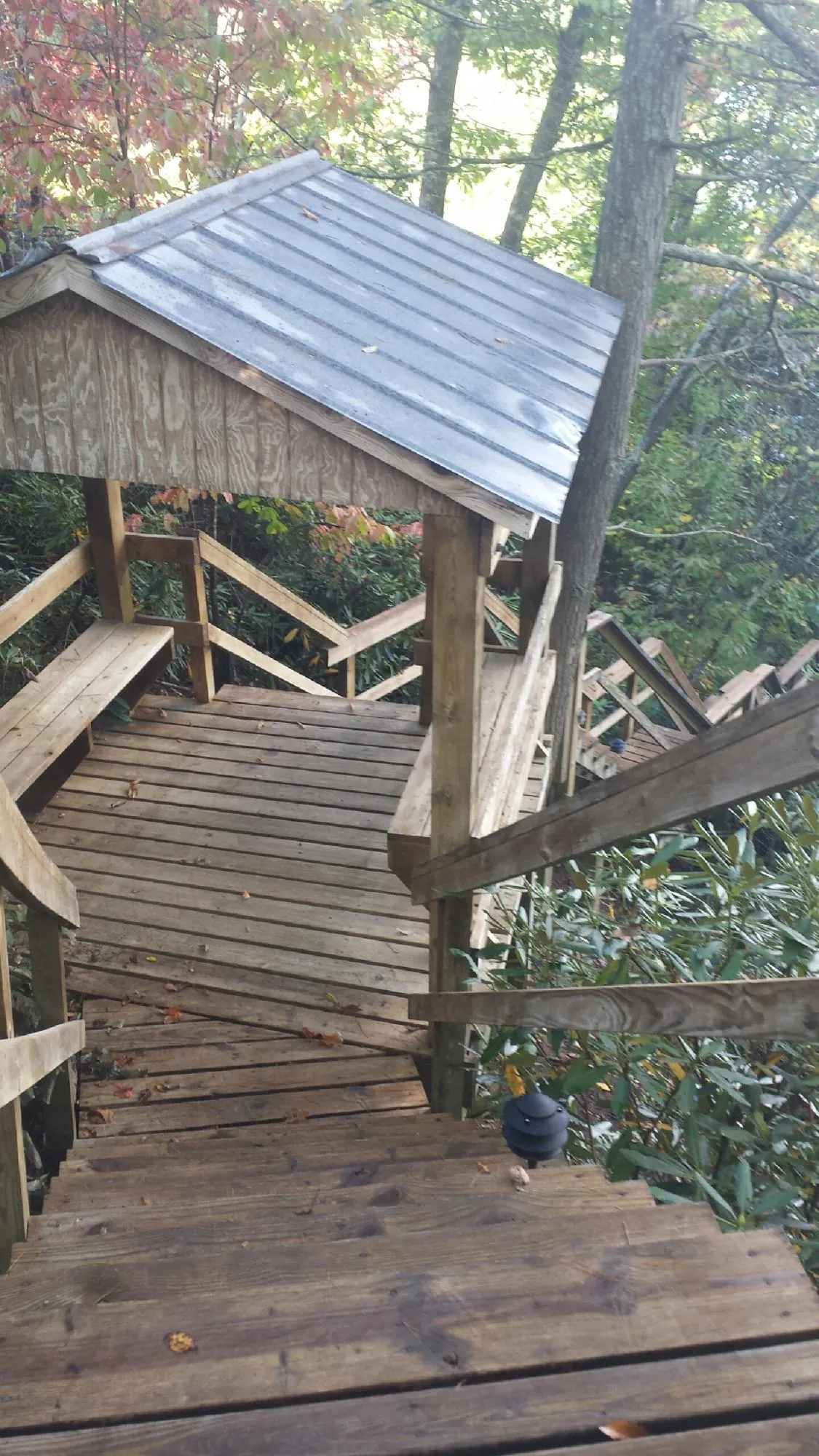 Metal roofed shelter over wooden steps on a wooded walkway — Skylight Repair & Installation work by our crew in Alamosa