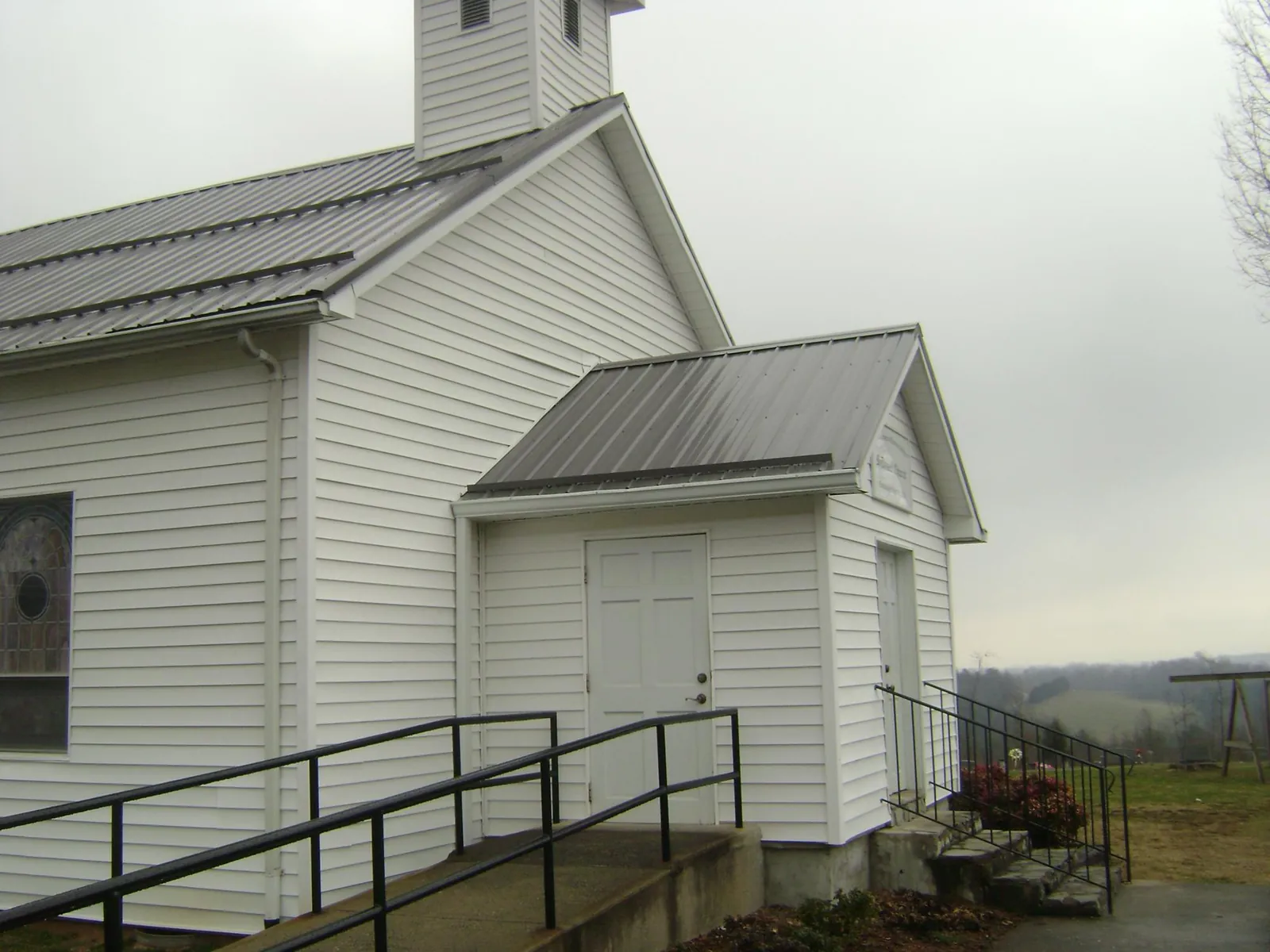Gray metal roof on a white clapboard church with a steeple in Alamosa