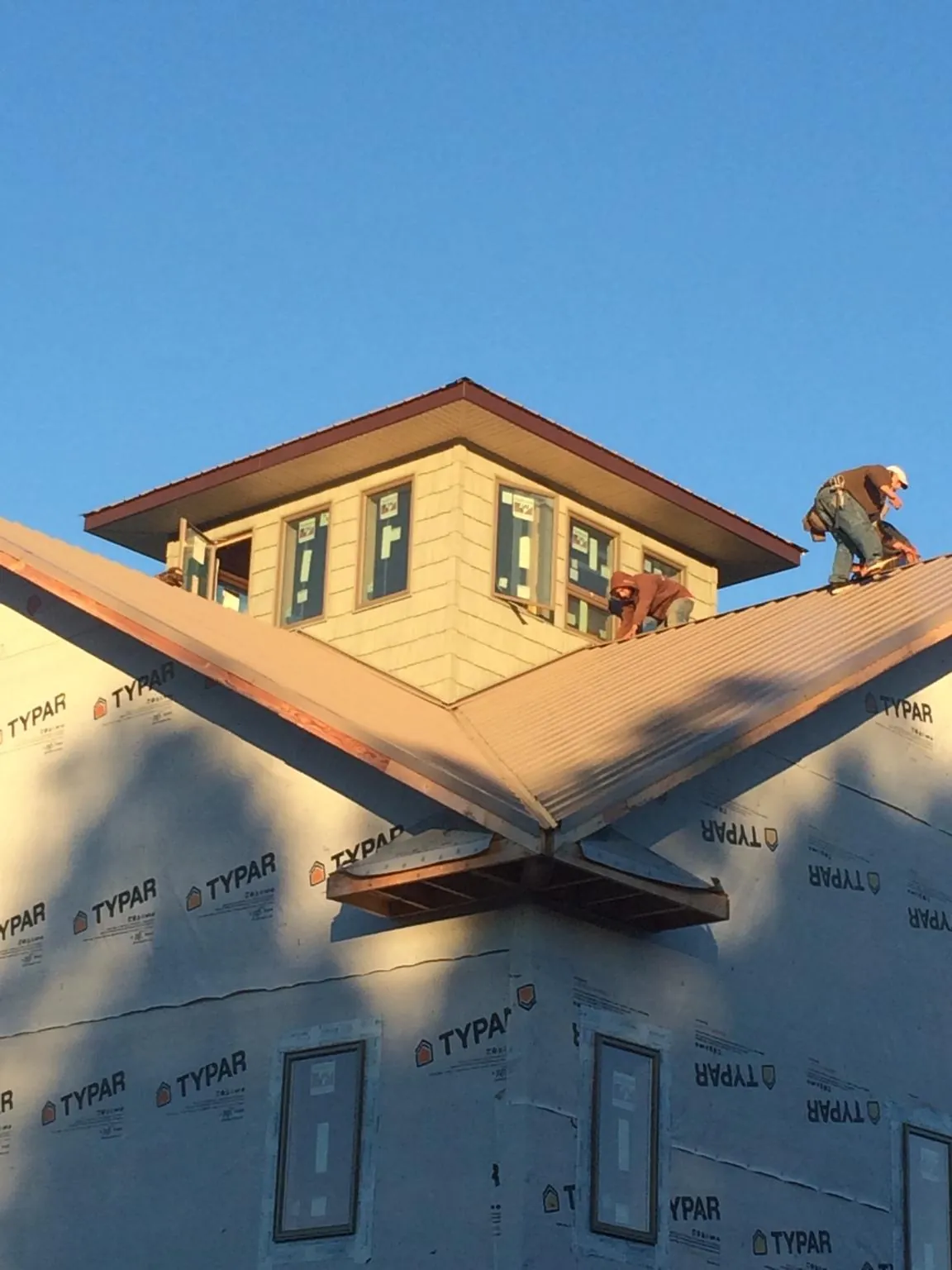 Roofers working around a rooftop cupola on a new metal roof at sunset — Roof Waterproofing in Alamosa by Roofing Brothers